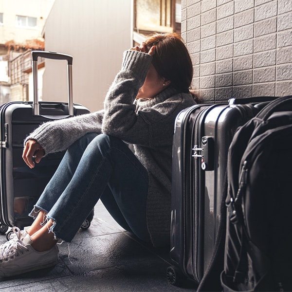 a woman sitting with feeling stressed while traveling with a lot of baggage