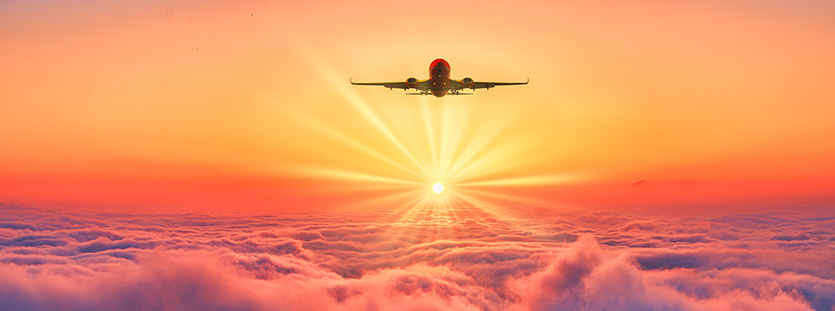 Plane flying into horizon at sunrise